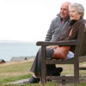 Image of elderly couple relaxing by the sea.
