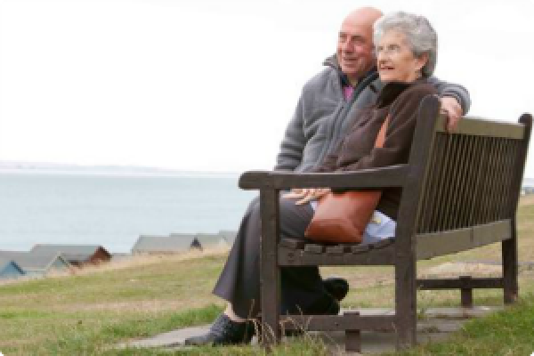Image of elderly couple relaxing by the sea.